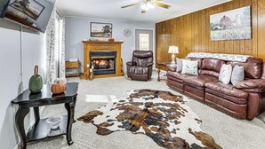 A living room with a fireplace, leather sofa, and a cowhide rug. - Families Welcome! Home w/ Fire Pit in Soddy-Daisy (Soddy-Daisy)