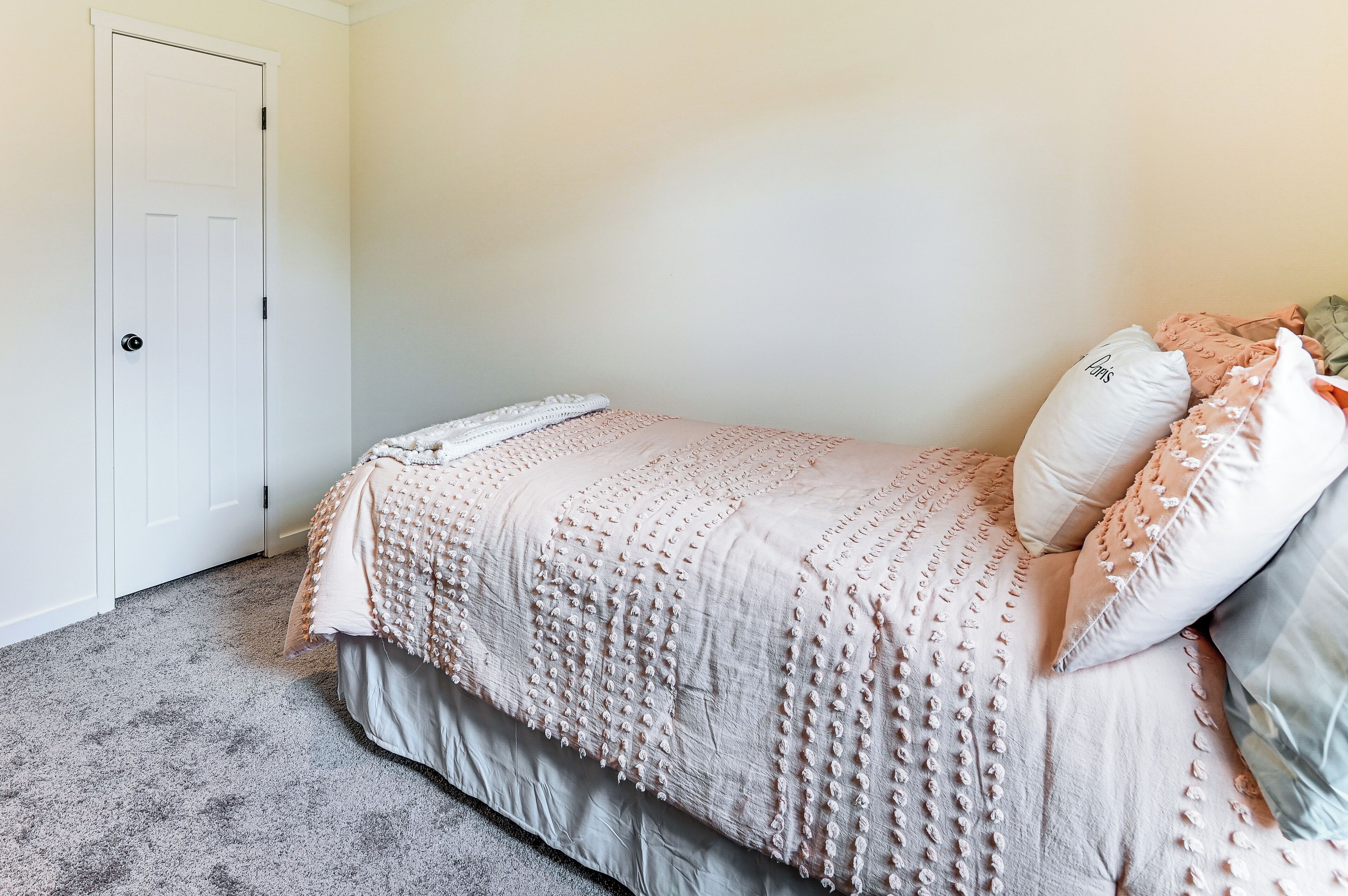 Een slaapkamer met een bed, een deur en een vloer met tapijt.