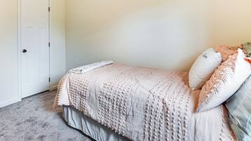 Een slaapkamer met een bed, een deur en een vloer met tapijt.
