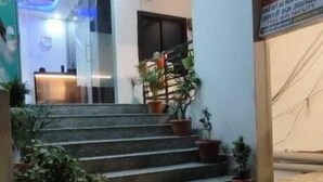 A hotel entrance with a reception desk, a staircase leading to the upper floor, and potted plants at the base. - Hotel Sri Kishan Kripa Inn (Prayagraj)