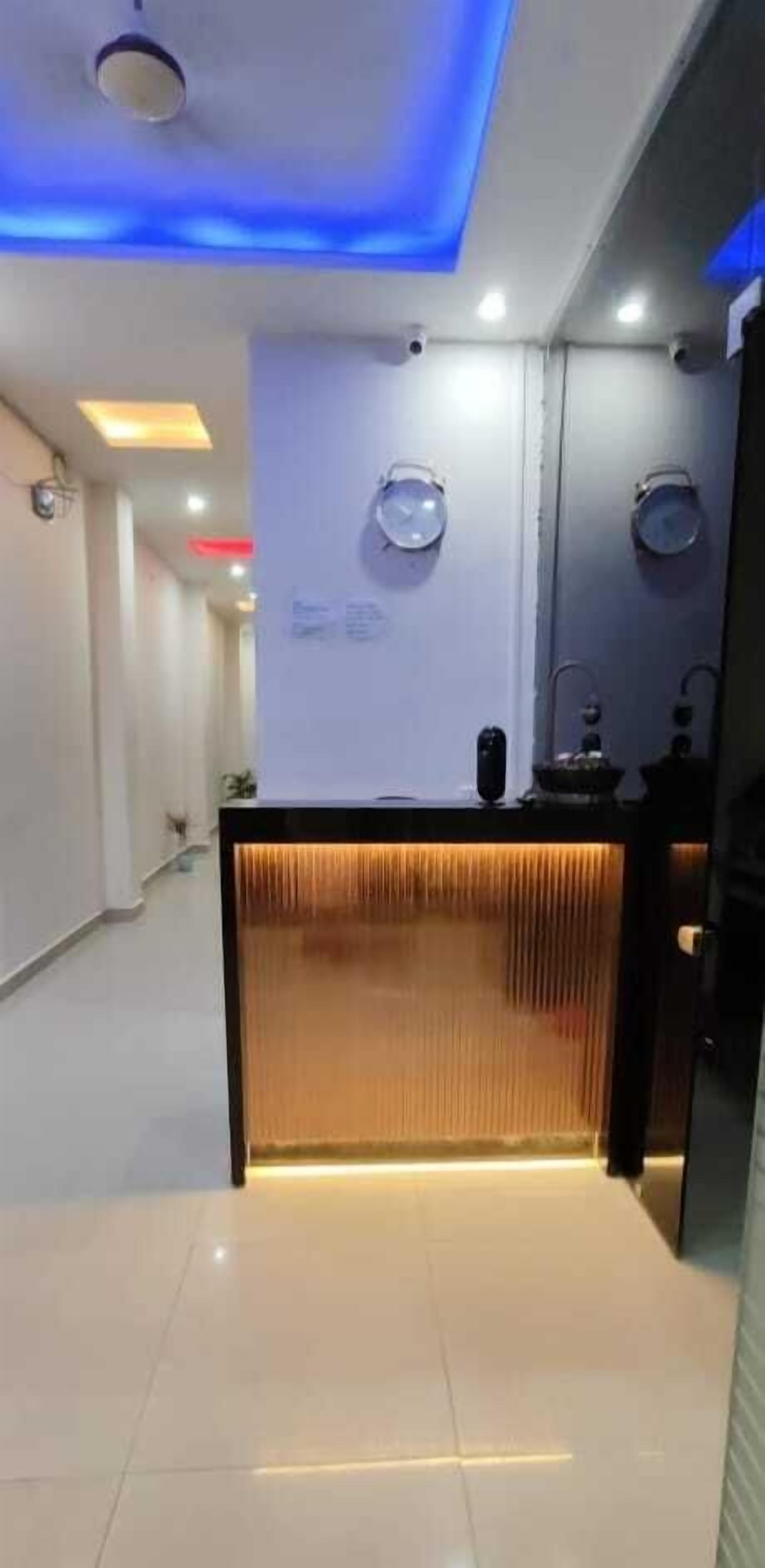 A modern reception area with a wooden reception desk, blue ceiling lighting, and a clock on the wall.