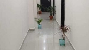 A clean, well-lit hallway with tiled floors and potted plants. - Hotel Sri Kishan Kripa Inn (Prayagraj)