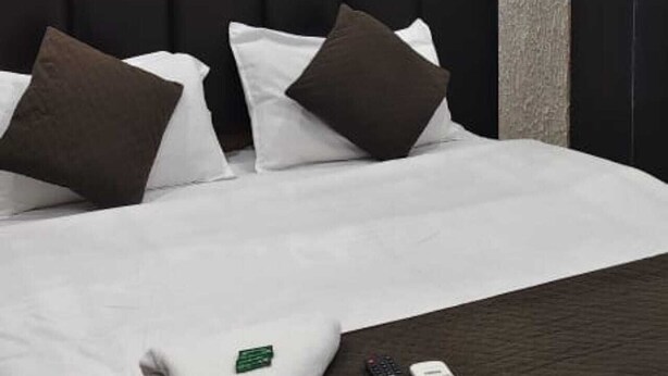 A hotel room with a black headboard, white bedding, and a few pillows. - Hotel Sri Kishan Kripa Inn (Prayagraj)
