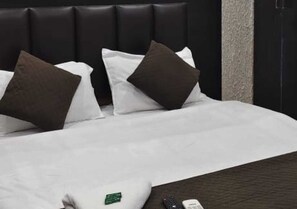 A hotel room with a black headboard, white bedding, and a few pillows. - Hotel Sri Kishan Kripa Inn (Prayagraj)