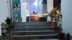 A hotel lobby with a reception desk, a staircase leading to the upper floor, and potted plants. - Hotel Sri Kishan Kripa Inn (Prayagraj)
