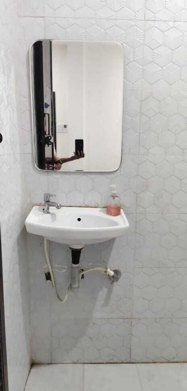 Een badkamer met een wit wastafel, een spiegel en een zeepdispenser.