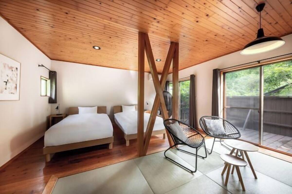 Una camera da letto con soffitto in legno, un letto, una sedia e un tavolo.