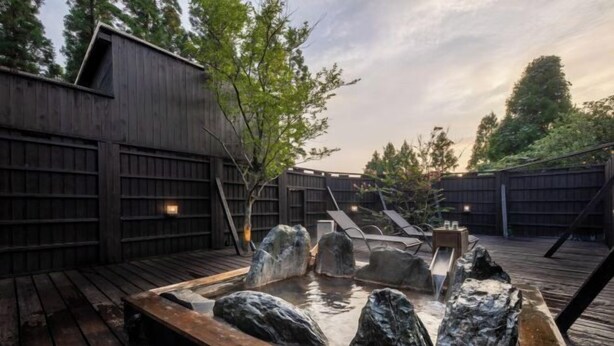 A hot tub with rocks, wooden deck, and a wooden fence. - Hanarenoyado Hanagokoro　ASO (Minamioguni)