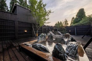 A hot tub with rocks, wooden deck, and a wooden fence. - Hanarenoyado Hanagokoro　ASO (Minamioguni)