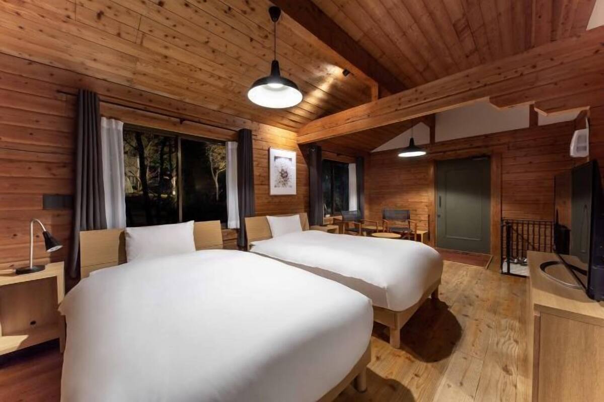 Una baita di legno con due letti, una scrivania e una sedia.