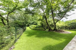 A pathway through a well-maintained garden with trees and a fence on one side. - Hanarenoyado Hanagokoro　ASO (Minamioguni)