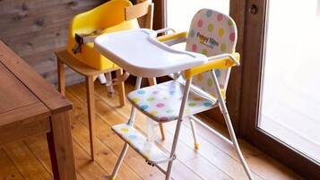 A room with a wooden floor, a wooden table, and two yellow chairs.