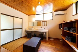 Un baño con piso de madera, un banco, un lavabo y un espejo.