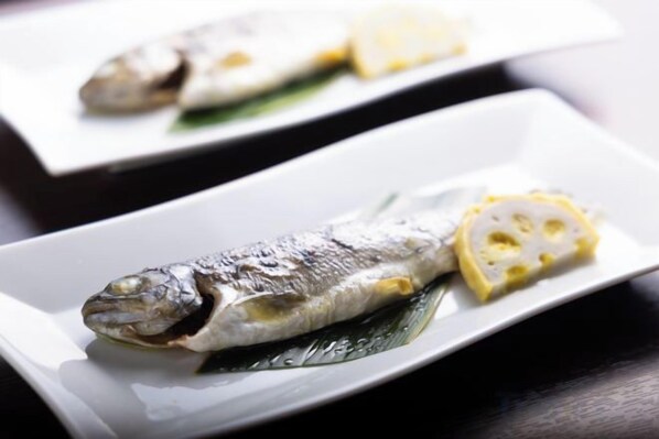 A plate with a whole fish and lemon slices.
