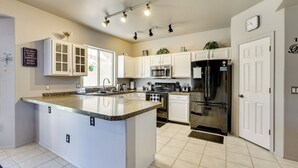 A modern kitchen with white cabinets, a granite countertop, stainless steel appliances, and a clock on the wall. - Labor Day Weekend Special: Flexible Check-In/Out! (Phoenix)
