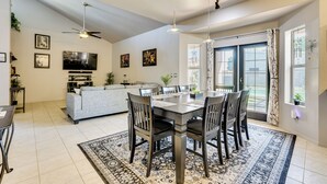 A spacious living area with a dining table, chairs, and a sofa. There is a ceiling fan, a flat-screen TV, and a window with curtains. - Labor Day Weekend Special: Flexible Check-In/Out! (Phoenix)