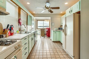 Una cocina con estufa a gas, pileta y ventilador de techo.