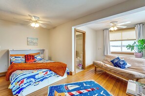 A bedroom with a bed, a sofa, a ceiling fan, and a window with curtains. - Steps to Nantasket Beach: Waterfront Gem w/ Patio! (Hull)