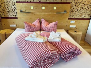 Een hotelkamer met een houten hoofdbord, geruit bedlinnen, twee kussens en een nachtkastje met een lamp.