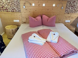 A hotel room with a wooden headboard, checkered bedding, and a wooden wall with a stone pattern.