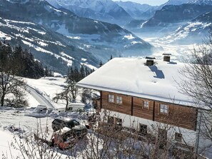 Un chalet en bois, dont le toit est recouvert de neige, niché au cœur d’un paysage montagneux.
