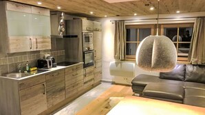 Une cuisine moderne avec des meubles en bois, un four encastré et un coin repas comprenant une table et des chaises.