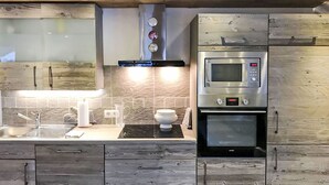 Une cuisine moderne équipée d’un four à micro-ondes encastré, d’un four traditionnel et d’une plaque de cuisson à induction noire.
