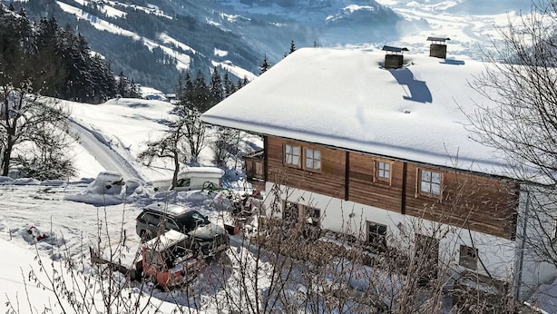 Een houten chalet met een met sneeuw bedekte dak, omgeven door een bergachtig landschap.