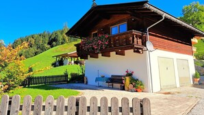 A wooden chalet with a balcony, a covered patio, and a fenced yard. - Beautiful private villa for 4 people with TV and terrace (Wildschönau)