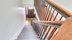 A wooden staircase with a handrail, leading to a landing with a door. - Explore & Work! Stylish Washington Heights Duplex (Newburgh)