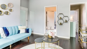 A modern living room with a light blue sofa, a round coffee table, and decorative mirrors on the wall. - Explore & Work! Stylish Washington Heights Duplex (Newburgh)