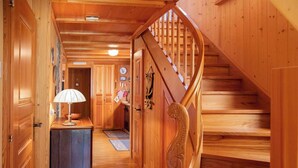 A wooden interior with a spiral staircase, wooden doors, and a kitchen area with a lamp.