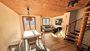 A spacious loft with a high ceiling, a dining area, a cozy seating area, and a spiral staircase. - Lovely apartment for 6 people with WIFI, balcony and panoramic view (Rabius)