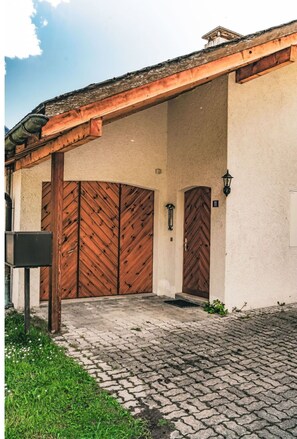Un edificio con acceso cubierto, dos puertas de madera, un buzón y un farol.