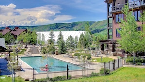 Zona de piscina con sillas de descanso, una terraza amurallada y vistas a las montañas.