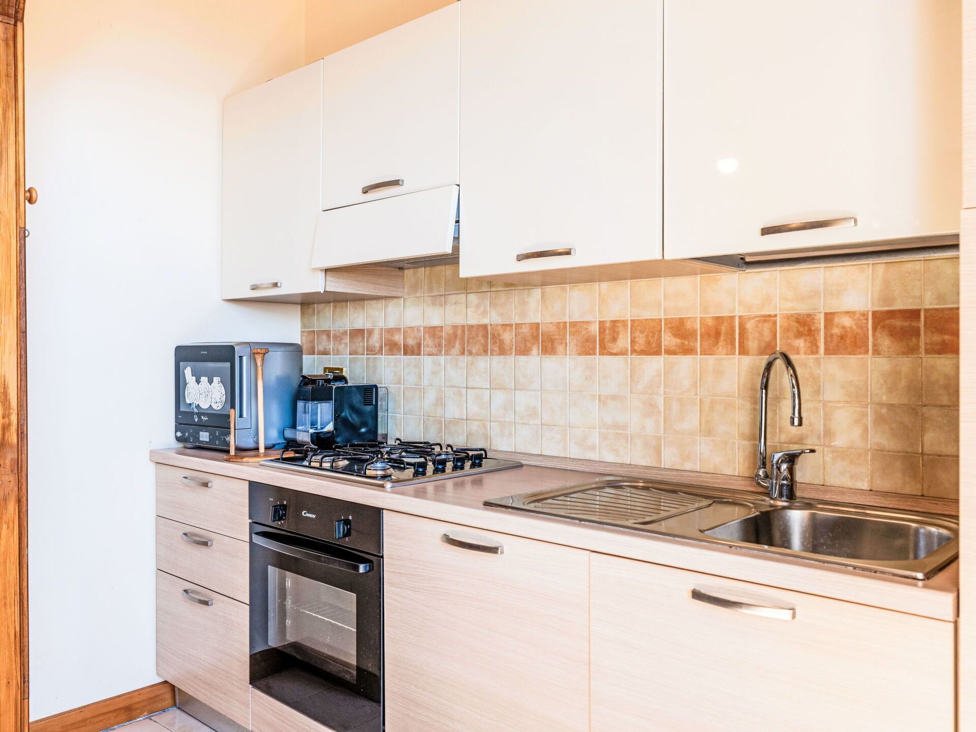 A modern kitchen with a gas stove, oven, coffee maker, and stainless steel sink.