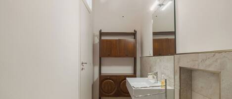 A compact bathroom with a wooden vanity, a white sink, and a mirror.