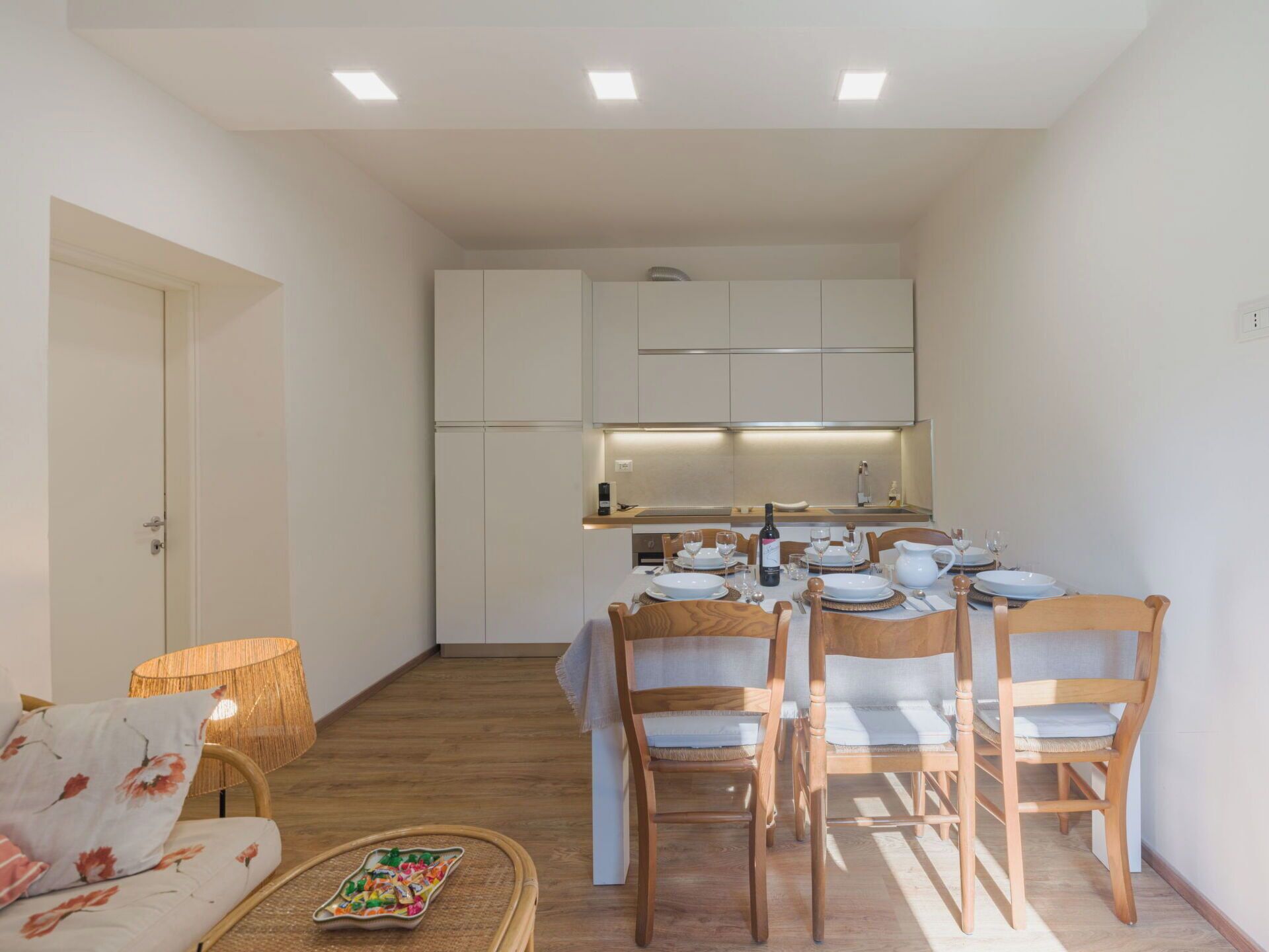 Een knus woongedeelte met een eethoek, kitchenette en een bank met een geweven mand.