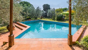 Ein rechteckiger Pool mit Fliesenbordstein, umgeben von einer hölzernen Pergola.