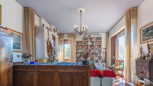 Ein geräumiges Zimmer mit einem großen Holztisch, einer Chandelier und einem Bücherregal voller Bücher.