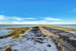 A coastal landscape with a sandy beach, a parking area, and a view of the sea. - 2 Portofino 1602 (Pensacola Beach)