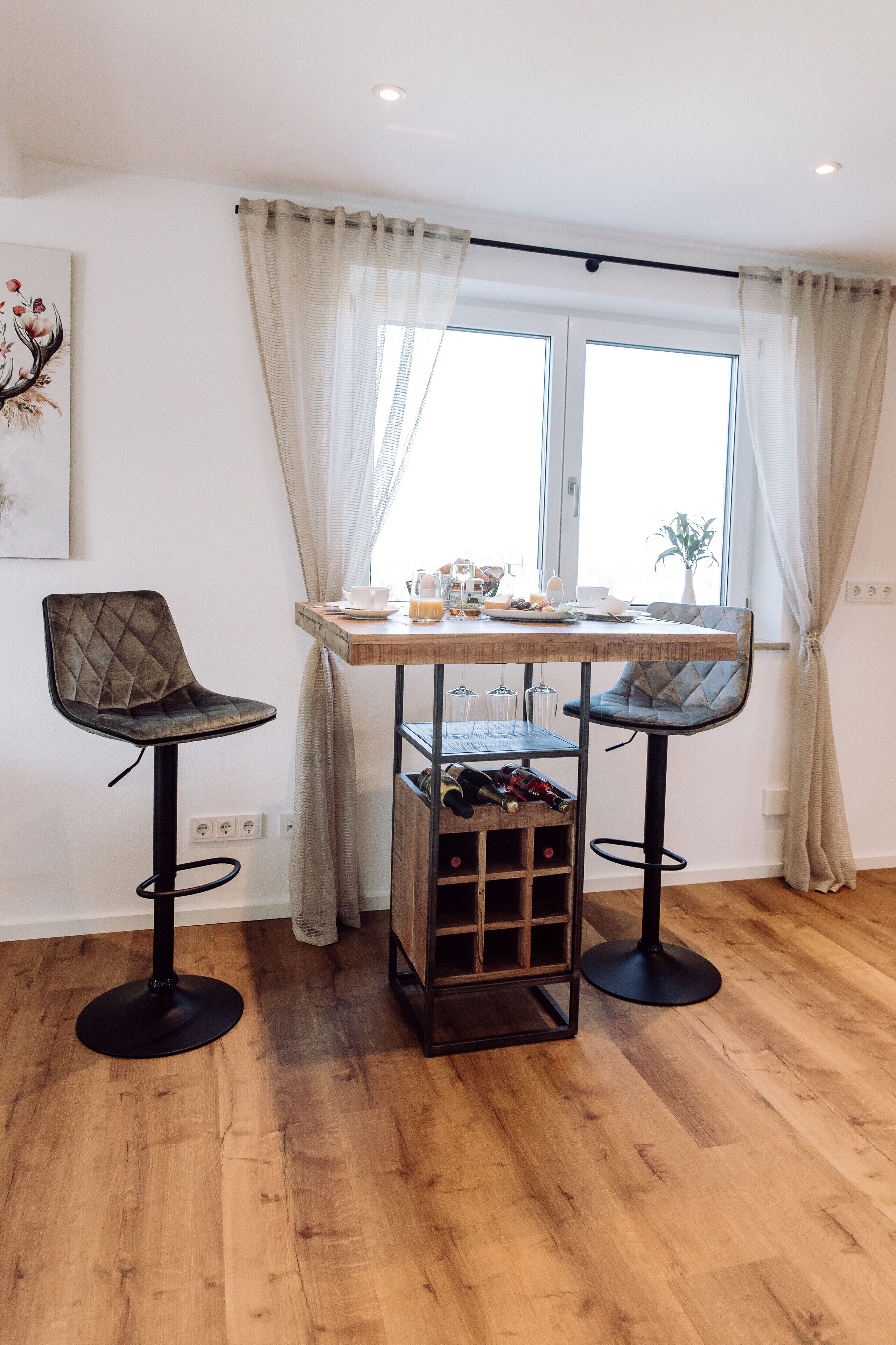 Een eethoek met twee stoelen, een tafel en een wijnrek.