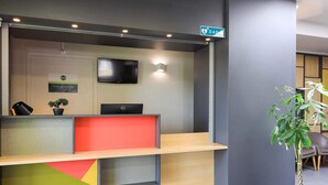 Una recepción con un televisor de pantalla plana, una planta en maceta y un letrero que indica una instalación DAF.