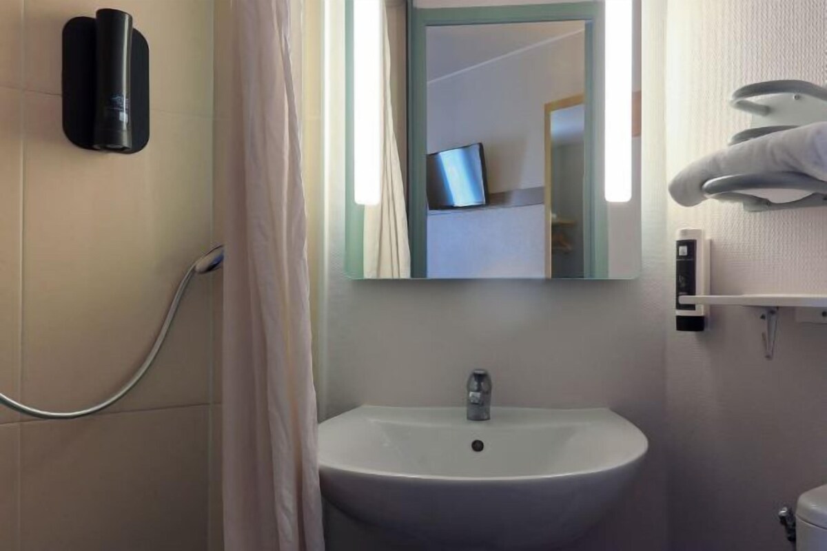 A bathroom with a sink, mirror, and towel rack.