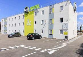 A B&B hotel with a colorful facade, a parking lot, and two cars parked in front.
