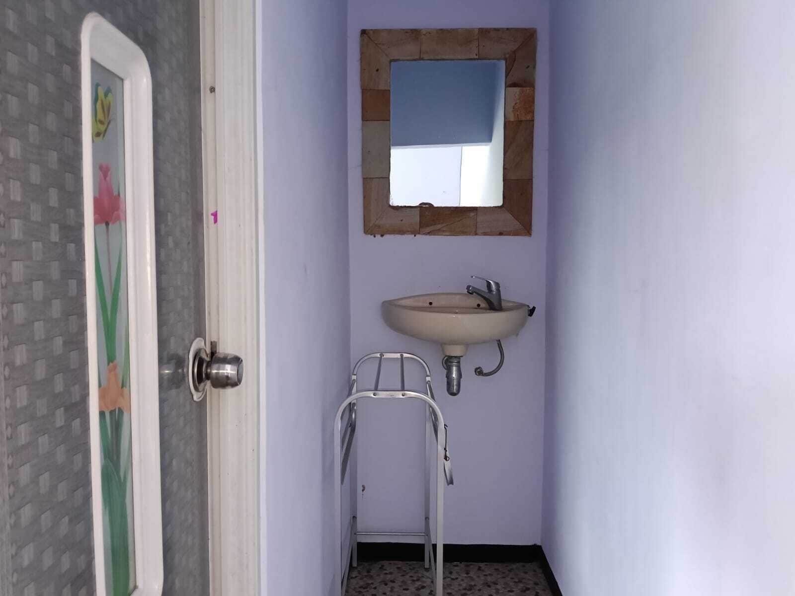 A bathroom with a sink, mirror, and a metal chair.