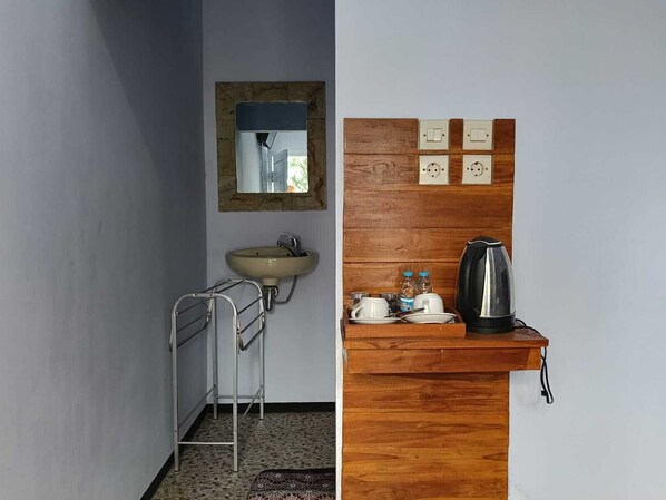 A bathroom with a sink, mirror, and wooden vanity with a kettle and cups. - Den Bagus Bromo (Ngadisari)