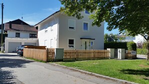 Un edifici residencial de dos pisos amb façana blanca, una tanca de fusta i un garatge.