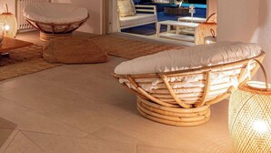 A modern living room with a fireplace, wicker furniture, and a view of the sea. - Villa Janas Eterea - Sardinia Unlimited (Portobello Di Gallura)
