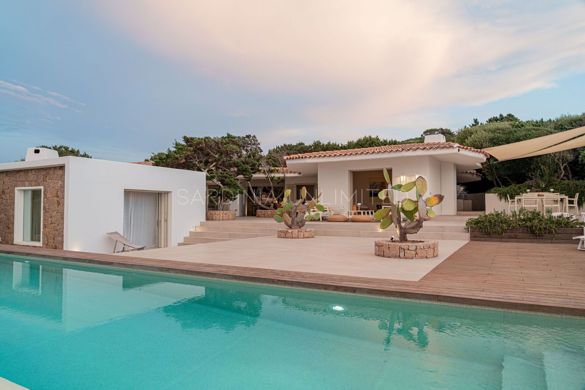 Eine moderne Villa mit Swimmingpool, Sitzgelegenheit im Freien und einem Garten mit Kakteen.